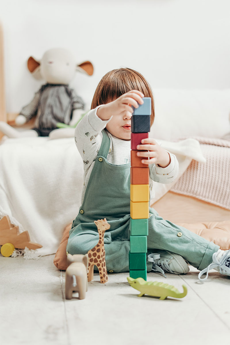 ребенок собирает башню из кубиков